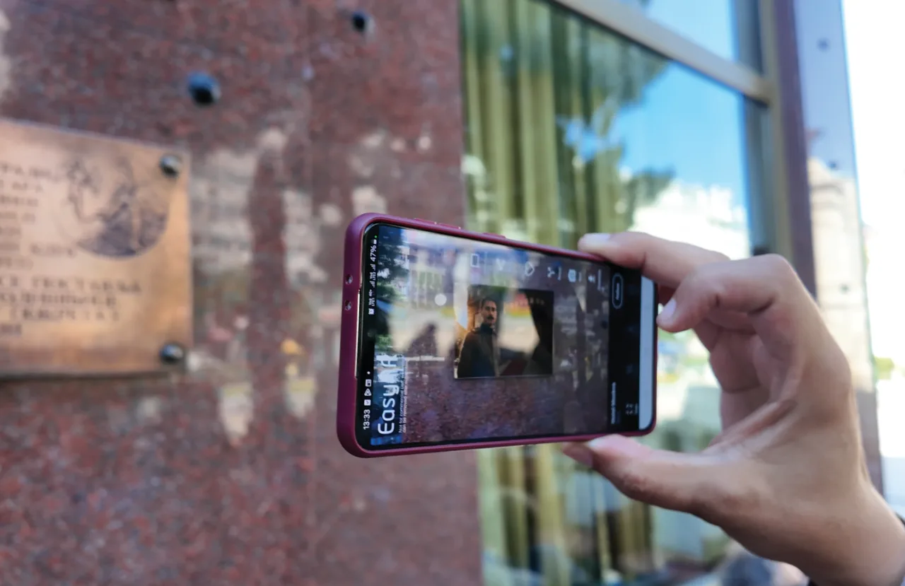 A phone revealing content from an image on a wall.
